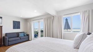 Une chambre d’hôtel avec un grand lit, un canapé et vue sur la plage.