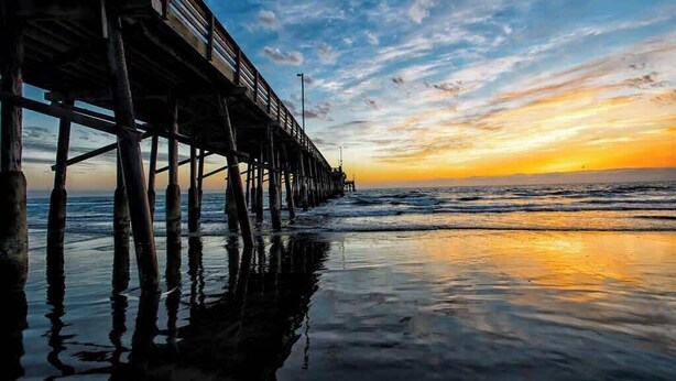 Un muelle se adentra en aguas tranquilas al atardecer.