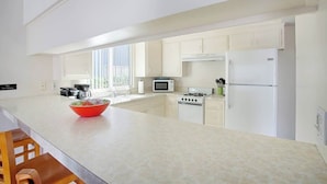Cocina moderna con armarios blancos, una isla grande, microondas, estufa y refrigerador.