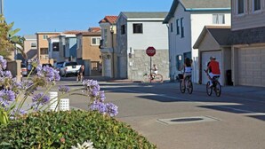 A residential street with houses, a stop sign, and cyclists. - 3612 Seashore | 4BR Ocean Escape | Steps from the Beach (Newport Beach)