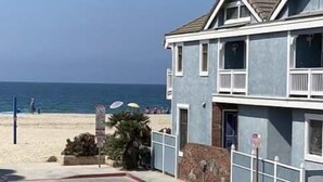 Een gebouw met twee verdiepingen en een balkon, nabij een strand.