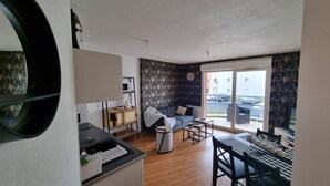 Ein kompakter Wohnbereich mit Sofa, Esstisch und einer kleinen Küchenzeile.