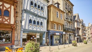 Eine Straße mit traditionellen Fachwerkhäusern, darunter ein Geschäft mit der Aufschrift 'IDEALE'.