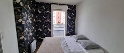 A bedroom with a bed, a window, and a view of a building outside.
