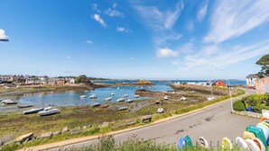 A coastal town with boats docked in a harbor, a road leading to the water, and buildings in the background. - Coastal paradise – House with sea view in Loguivy (Ploubazlanec)