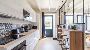 A modern kitchen with patterned backsplash, a built-in oven, and a bar area with stools. - Coastal paradise – House with sea view in Loguivy (Ploubazlanec)