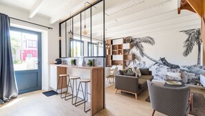 A modern living space with a kitchen area, a dining area, and a seating area with a sofa and armchairs. - Coastal paradise – House with sea view in Loguivy (Ploubazlanec)