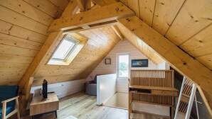 Une chambre confortable située dans les combles, avec des poutres en bois, un puits de lumière, un bureau, une chaise et un lit.