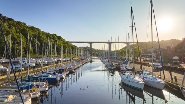 A marina with numerous boats docked along a river, a bridge in the background, and a forested hillside. - Pleasant 2-room apartment close to shops and train (Saint-Brieuc)