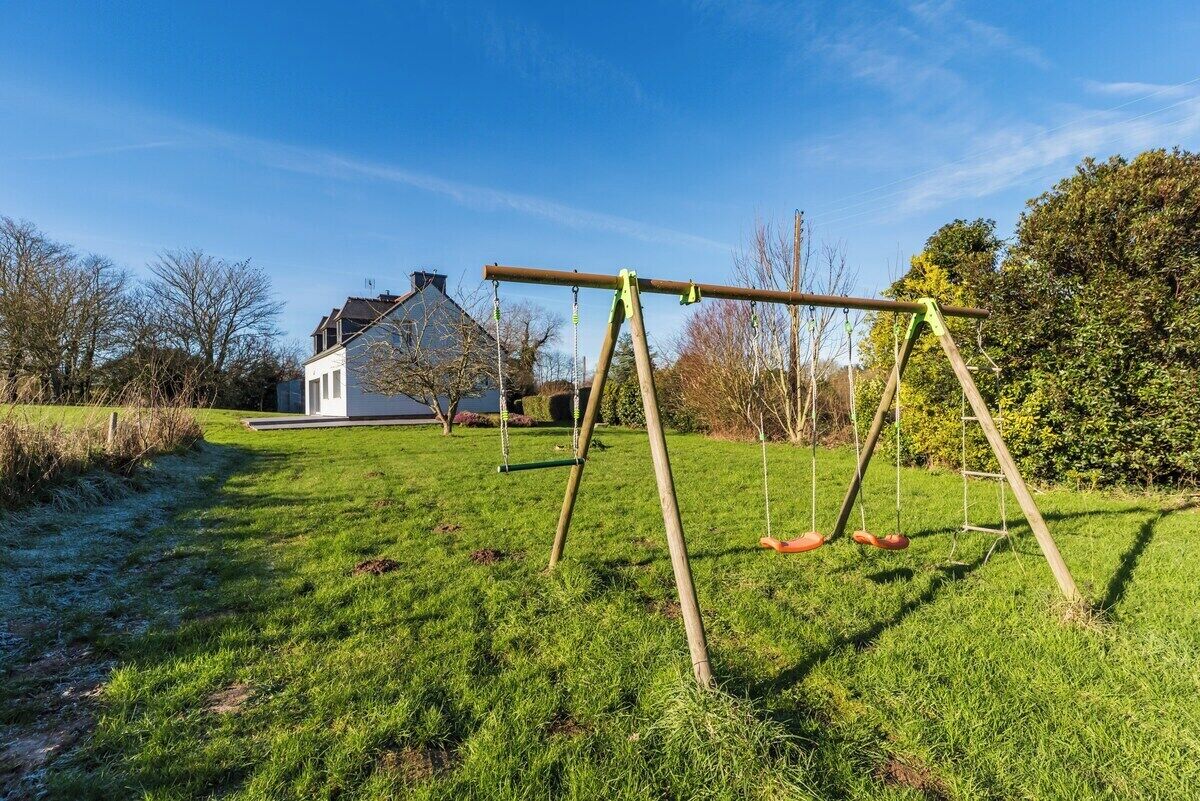En gräsyta med en gunga och ett hus i bakgrunden.