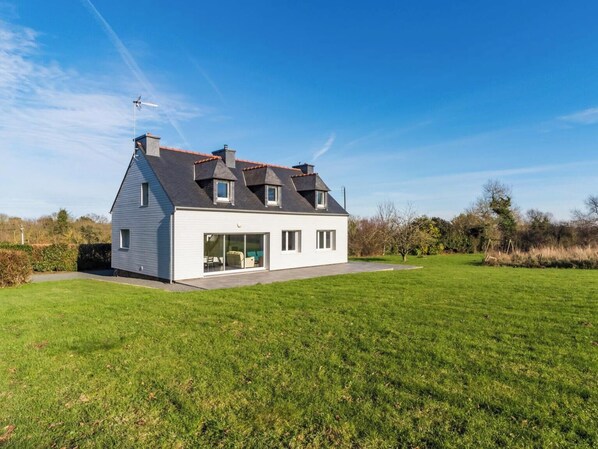 Ein modernes, zweistöckiges Haus mit großem Rasen, Garage und Schornstein.