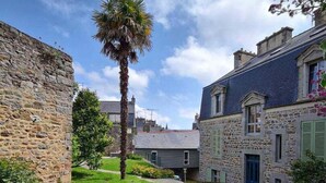 A courtyard with stone buildings, a palm tree, and a clear sky. - Exceptional apartment - close to the sea (Saint-Brieuc)