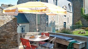 An outdoor patio with a table, chairs, and a striped umbrella. - Exceptional apartment - close to the sea (Saint-Brieuc)