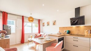 Een moderne keuken met een eethoek, houten kastjes en een aan de muur bevestigde televisie.