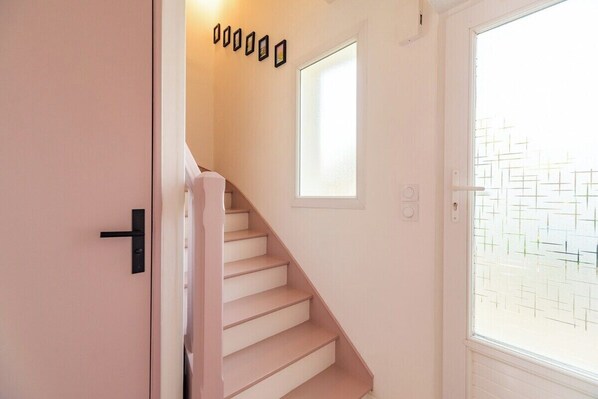 Eine Treppe führt zu einem Zimmer mit Fenster und Tür.