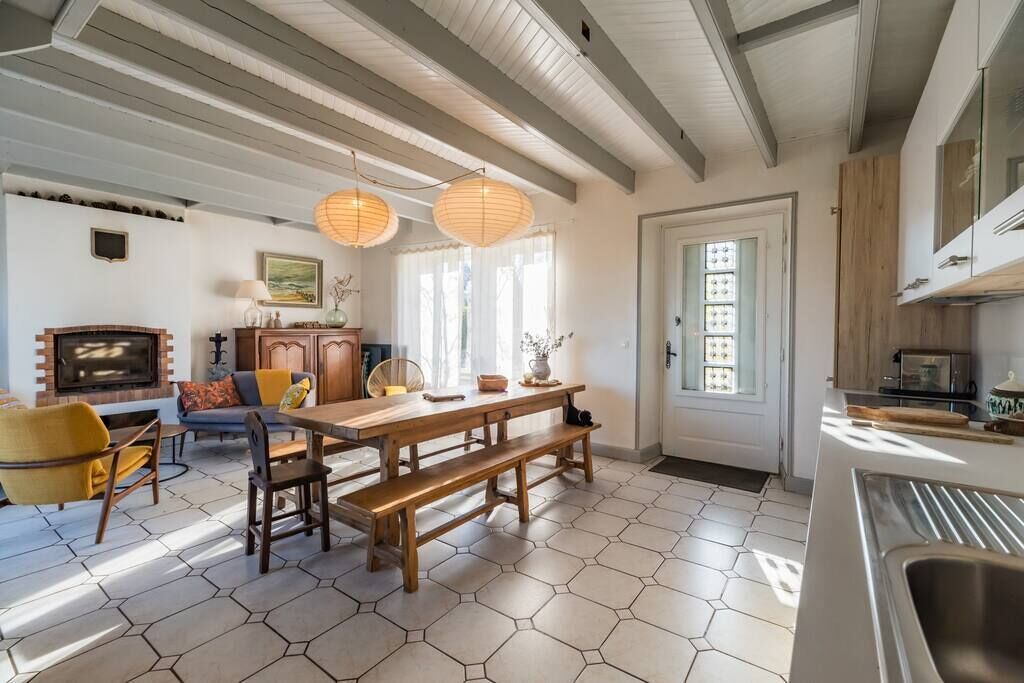 Une cuisine moderne avec une table et un banc en bois, un four encastré et une fenêtre avec des rideaux.