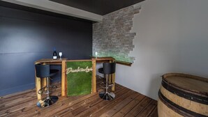 A bar area with two stools, a wooden counter, and a neon sign. - Vacation home in Pordic - close to the sea (Pordic)
