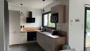 A modern kitchen with a dishwasher, microwave, and a window providing natural light. - Vacation home in Pordic - close to the sea (Pordic)