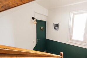 Stairs lead to a room with a green door, a framed picture, and a window.