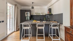 A modern kitchen with a central island, bar stools, a microwave, and a built-in oven. - Villa Giovanna con Piscina by Wonderful Italy (Castellammare del Golfo)