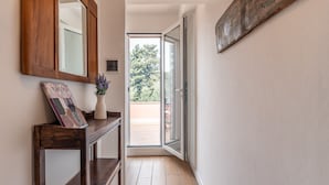 A hallway with a wooden console table, a mirror, and a view of the outdoors through a glass door. - Villa Giovanna con Piscina by Wonderful Italy (Castellammare del Golfo)