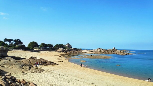 Una playa costera con terreno rocoso y aguas azul turquesa.