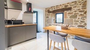 Una cocina moderna con una pared de acento de piedra, una mesa de comedor de madera y taburetes de bar.
