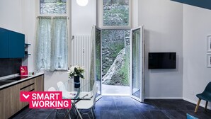 A modern kitchen with a dining area, a large window with a view of a rocky landscape, and a flat-screen TV mounted on the wall. - Loft Garibaldi by Wonderful Italy (Genova)