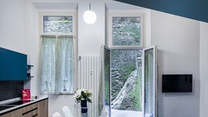 Une cuisine moderne avec un coin repas, une grande fenêtre offrant une vue sur un paysage rocheux et un téléviseur à écran plat fixé au mur.
