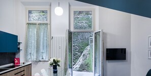 Una cocina moderna con comedor, un amplio ventanal con vistas a un paisaje rocoso y un televisor de pantalla plana montado en la pared.