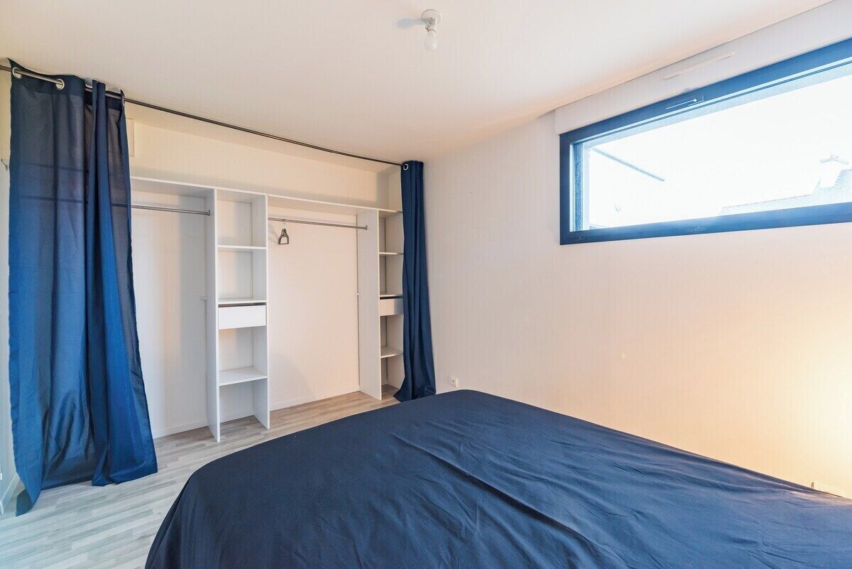 A bedroom with a bed, a wardrobe, and a window.