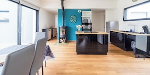 Uma cozinha moderna com uma ilha central, fogão e área de refeições com mesa e cadeiras.