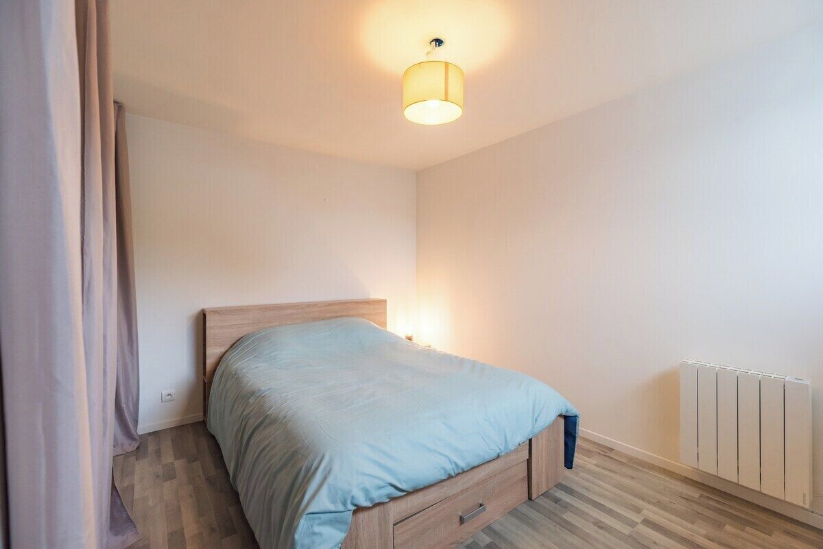 Une chambre à coucher avec un lit, une table de chevet, une lampe et un radiateur.