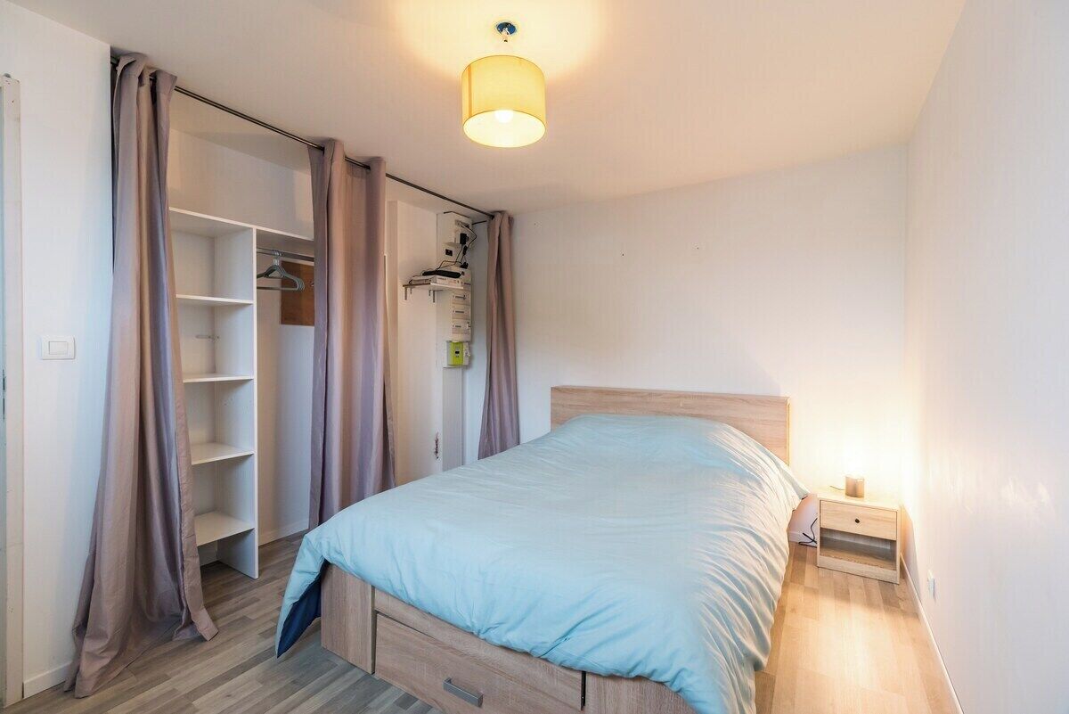Un dormitorio con cama, mesita de noche, armario y una lámpara en el techo.