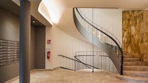 A modern interior with a spiral staircase, marble flooring, and a fire extinguisher on the wall. - Carignano Luxury Suite by Wonderful Italy (Genova)