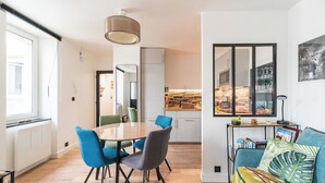 A modern living space with a dining area, kitchen, and a sofa with colorful cushions. - L'Escale Paimpolaise 2 Stars - historic center (Paimpol)