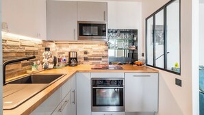 A modern kitchen with a built-in oven, microwave, and a large window. - L'Escale Paimpolaise 2 Stars - historic center (Paimpol)