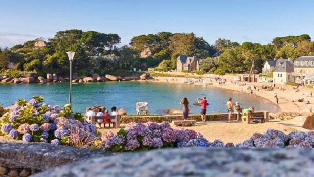 Une ville côtière avec une plage, des gens qui se détendent et des bâtiments en arrière-plan.