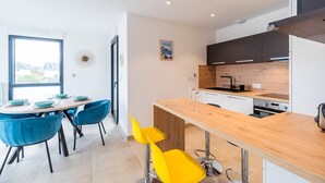 Une cuisine moderne avec un plan de travail en bois, des meubles noirs et une fenêtre donnant sur un paysage urbain.