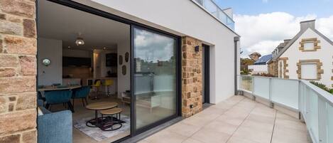 Uma casa moderna com porta de vidro que dá para uma sala de jantar com cadeiras azuis e uma mesa redonda.