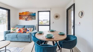 Un espace repas moderne avec une table ronde, des chaises bleues et un canapé bleu agrémenté de coussins colorés.