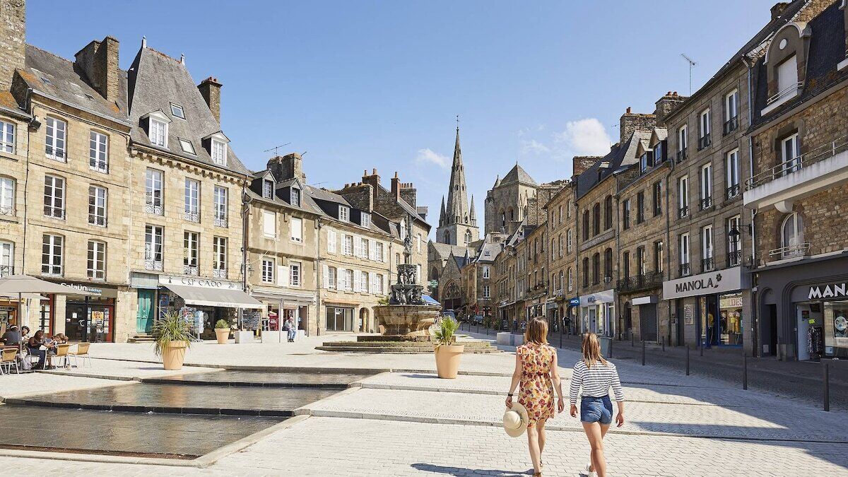 Una plaza histórica con adoquines, una fuente y arquitectura europea tradicional.