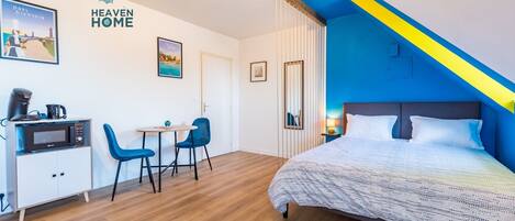 A room with a bed, a desk with a microwave, two chairs, and a small table.