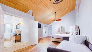 Un'ampia camera da letto con soffitto in legno, un letto, una cassettiera e una toeletta.