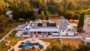 Un'ampia casa a più piani con un patio spazioso, una piscina e un prato ben curato.
