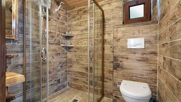 Un baño con ducha de vidrio, azulejos de madera, un inodoro y un estante pequeño con artículos de aseo.
