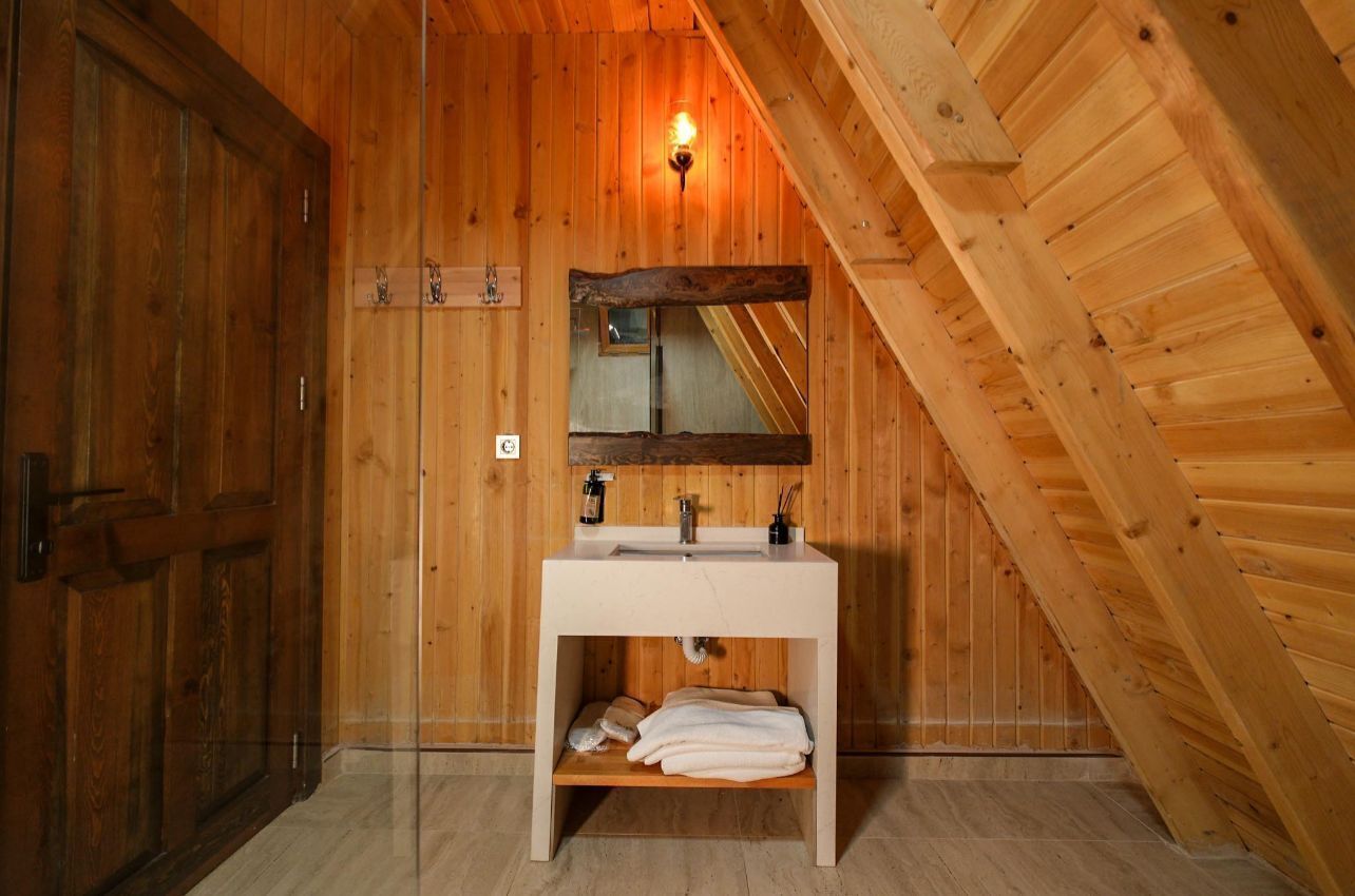 A wooden bathroom with a white sink, a mirror, and a towel rack.