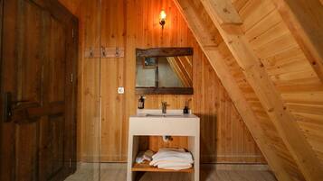 A wooden bathroom with a white sink, a mirror, and a towel rack.