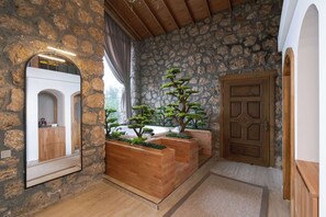A stone-walled hallway with wooden planters, a mirror, and a wooden door. - Botanik Gol Evleri (Bucak)