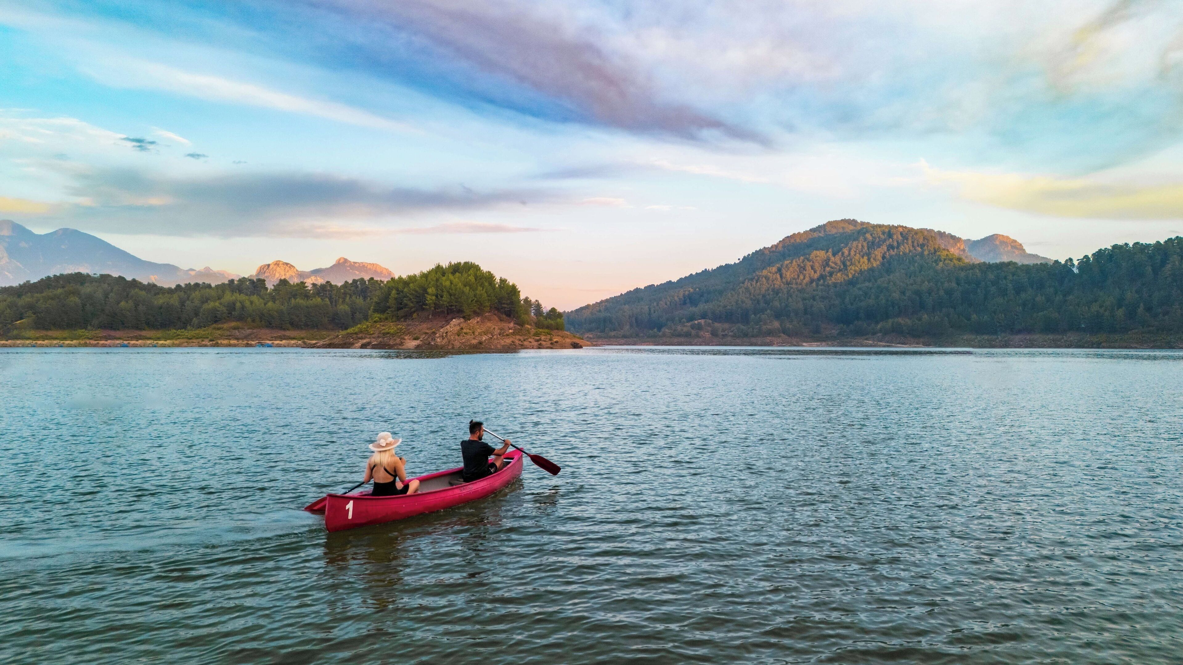 Un lago tranquilo con dos personas en una canoa roja.
